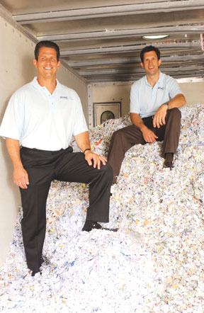 Brian and Mike Gumbko posing on a pile of shredded documents