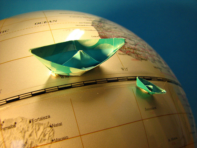 Small blue paper boats sitting on the surface of a globe