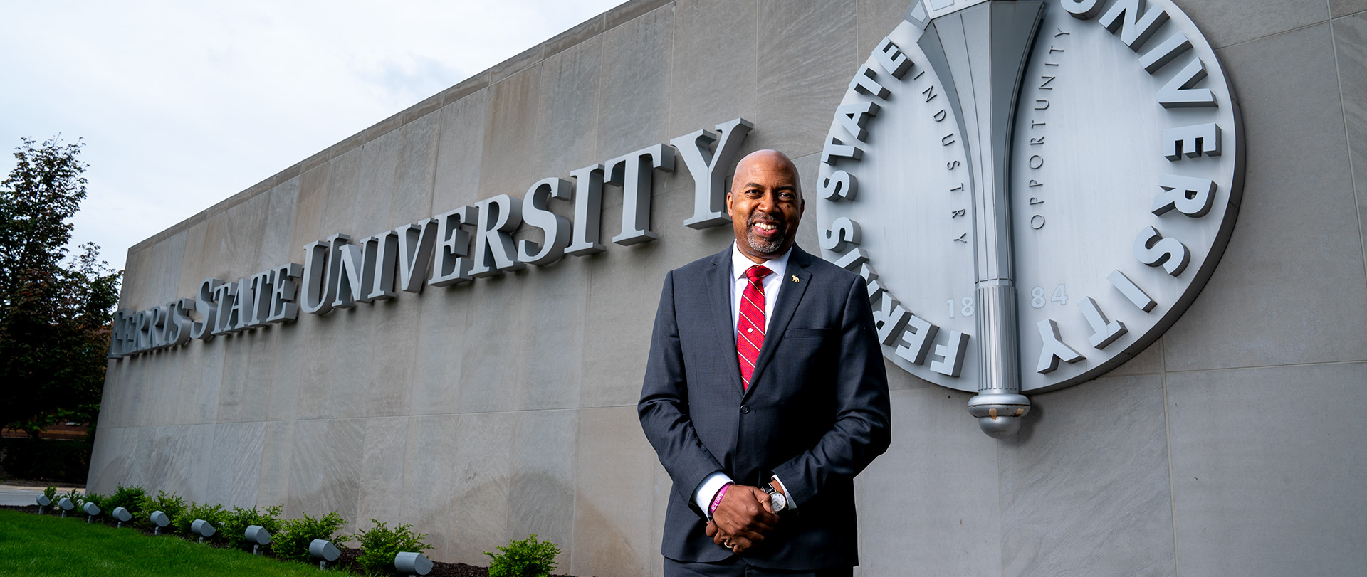 President Bill Pink in front of the Ferris State University logo wall