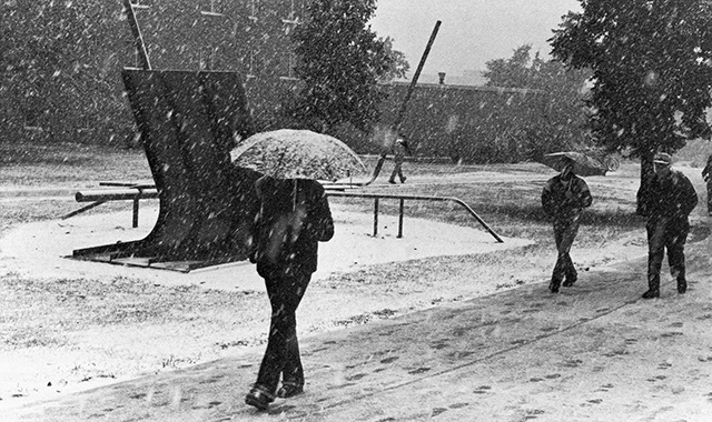 students walking in snow past I am Late sculpture