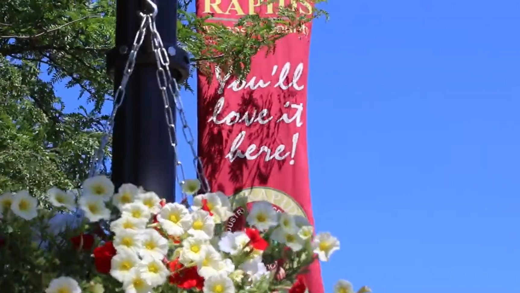 Image of flowers and Big Rapids downtown lightpost sign reading "You'll love it here!"