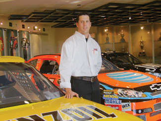 Jim Suth poses in a garage full of stock cars