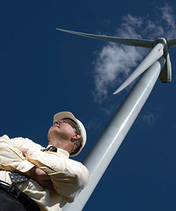 Scott Frederick standing beneath a wind turbine