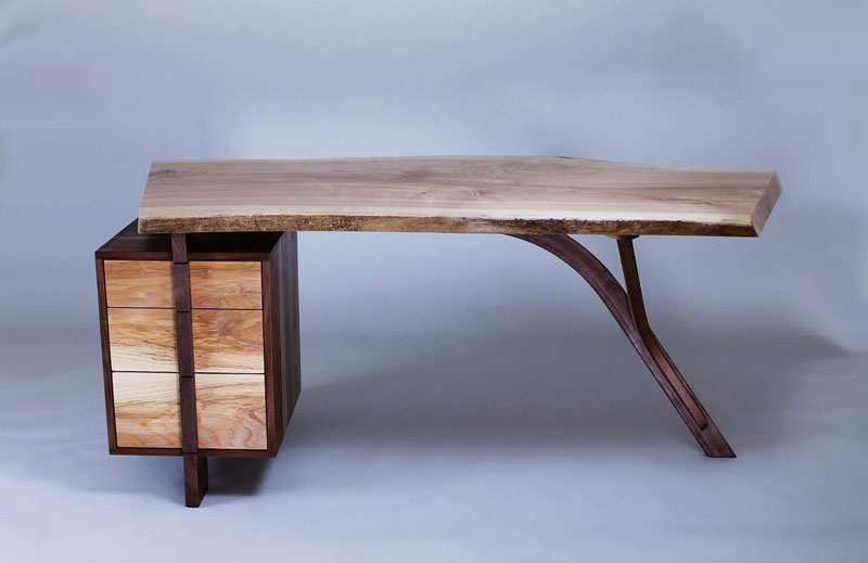 A photograph of a custom wood table, stained a dark brown and placed in front of a blue background