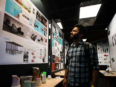 A man wearing a plaid shirt looking at a wall of artwork