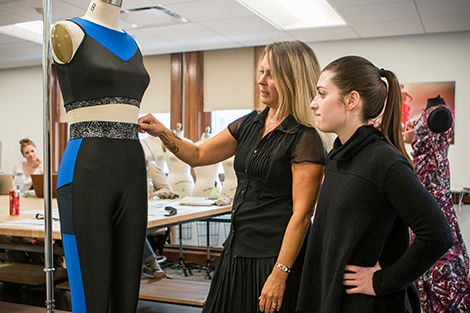 Professor teaching a student in front of a dress model