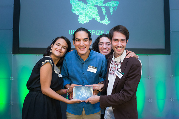 A group of young people huddled together showing off a trophy