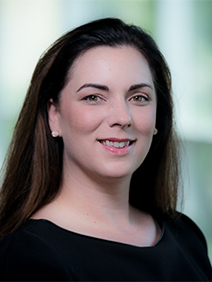 Portrait of a woman with long dark brown hair and a wide neck black shirt