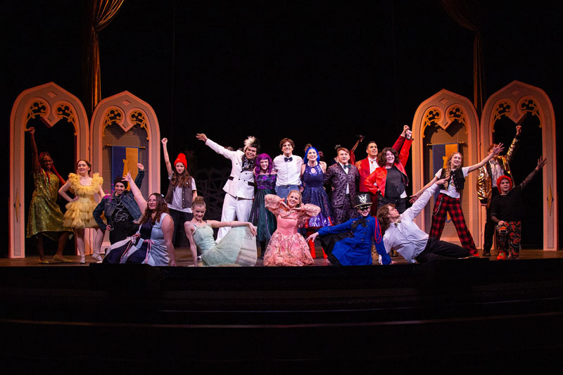a group of theatre actors posing on stage in colorful costumes