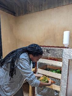 A woman with long dreadlocks sorts vegetables into a bin