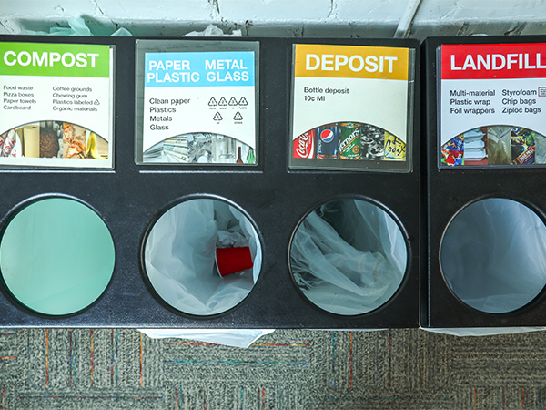 A waste bin with four compartments for sorting recyclable and compostable materials.
