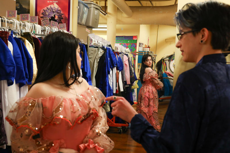 A fashion designer standing next to a theatre actor wearing an elaborate pink dress