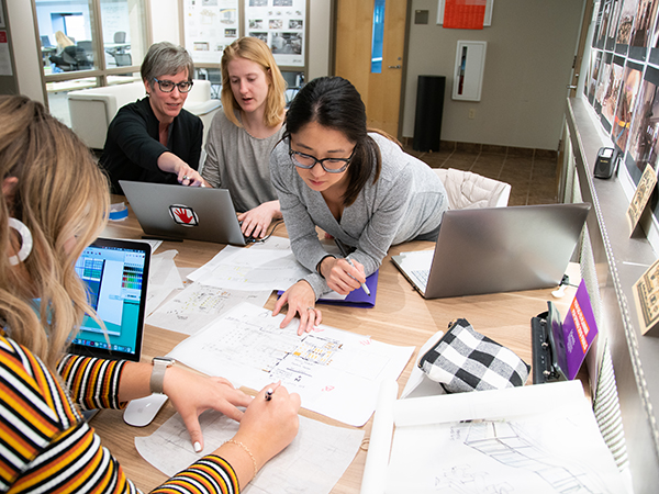 A group of people huddled around a computer screen
