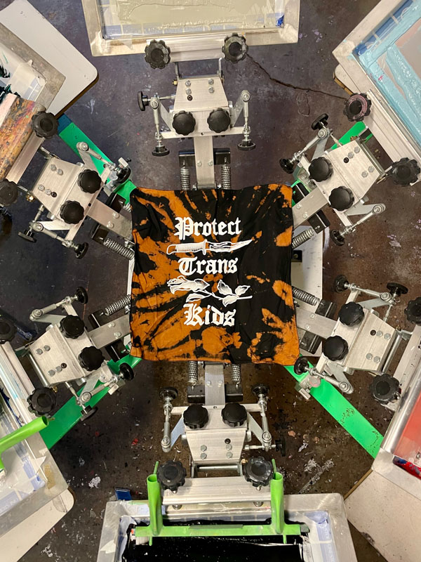 a screen printing press with a t-shirt reading protect trans kids
