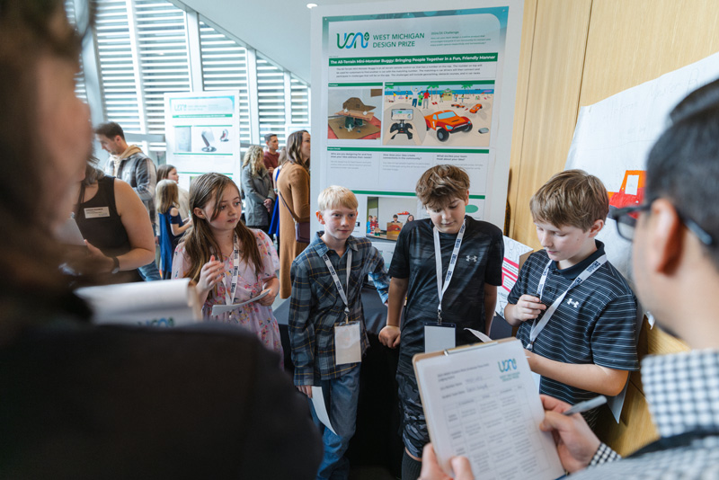 A group of young people presenting an idea on a large informational poster to a group of adults