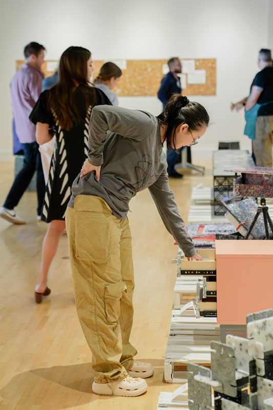 A person bending at the waist to examine a table