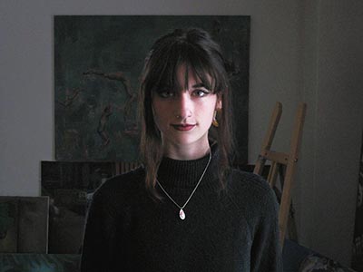 A woman wearing a black turtleneck looks into the camera