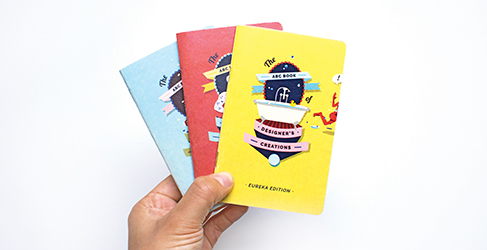 A hand holding three small booklets