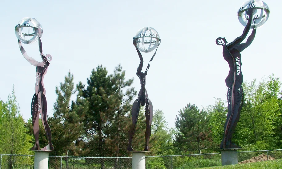 statue of three figures each holding a round metal ball