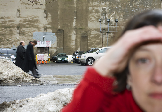 photo of woman peering in blurry foreground and people walking in background