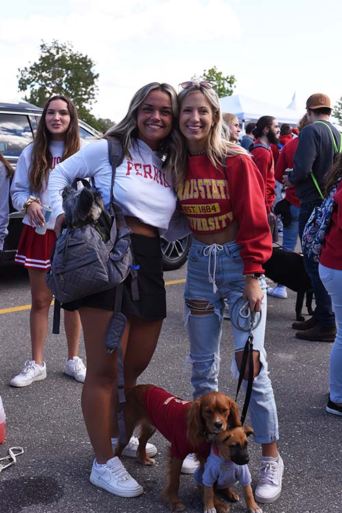 two girls at a tailgate and their dogs