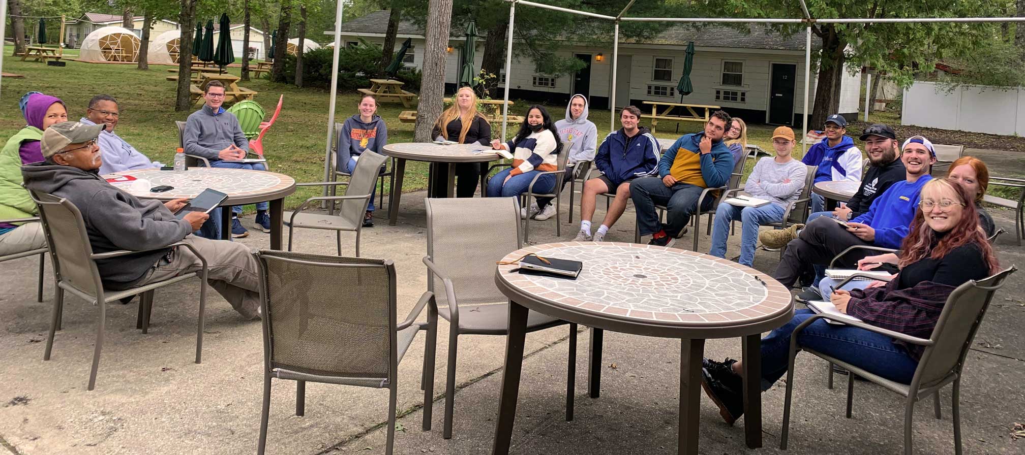 Students from the Small Town Studio project sit around a patio, smiling.