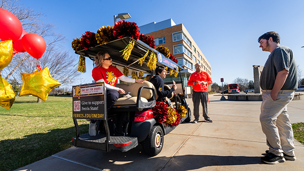 Ferris State student interacts with campus figures offereing prizes for Trivia on One Day for Dawgs