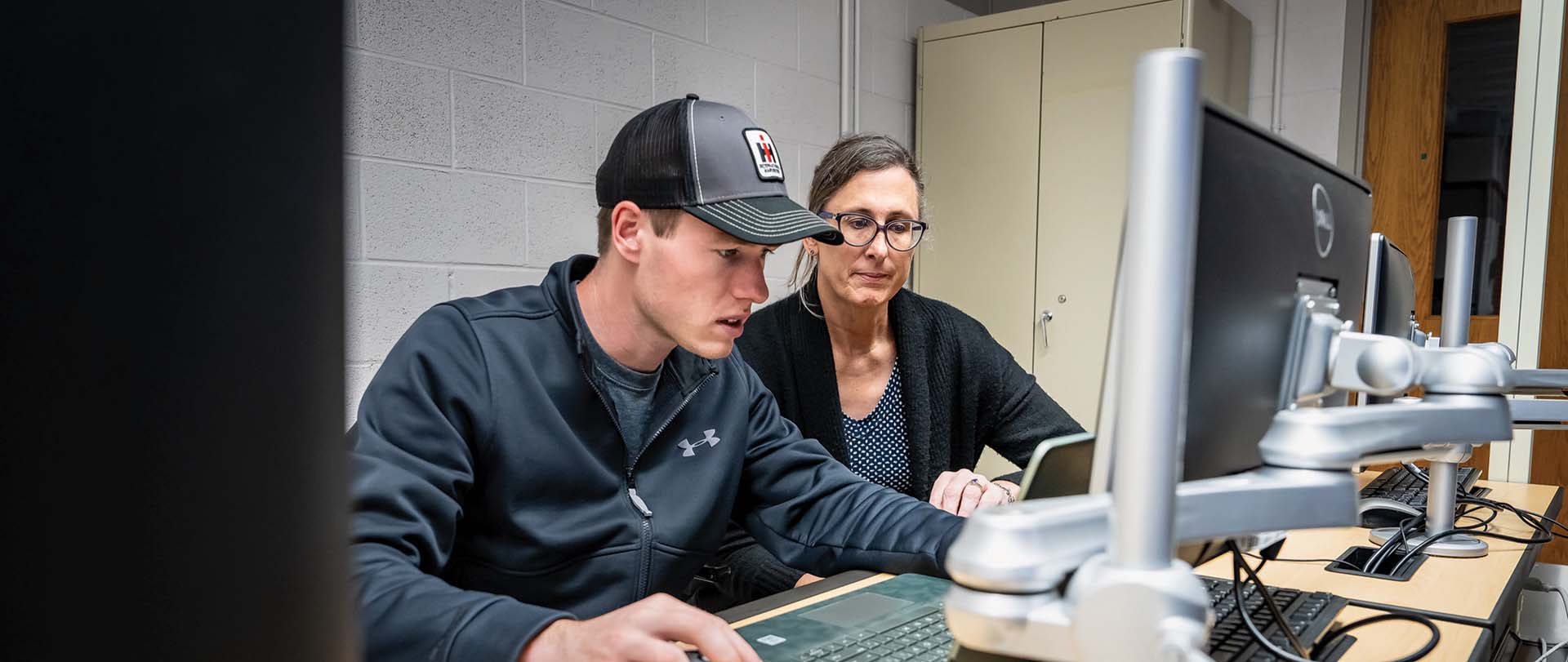 Staff helping student on a computer