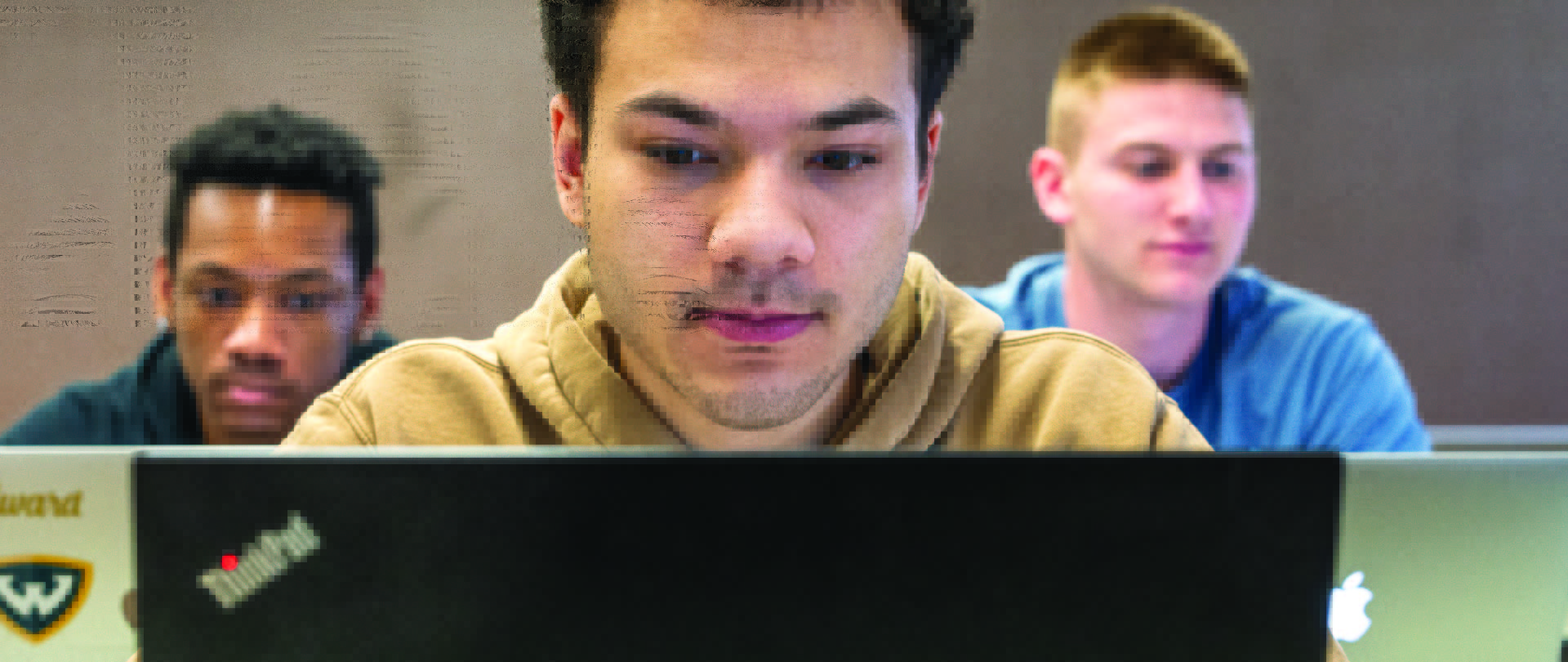 three students on laptop in classroom