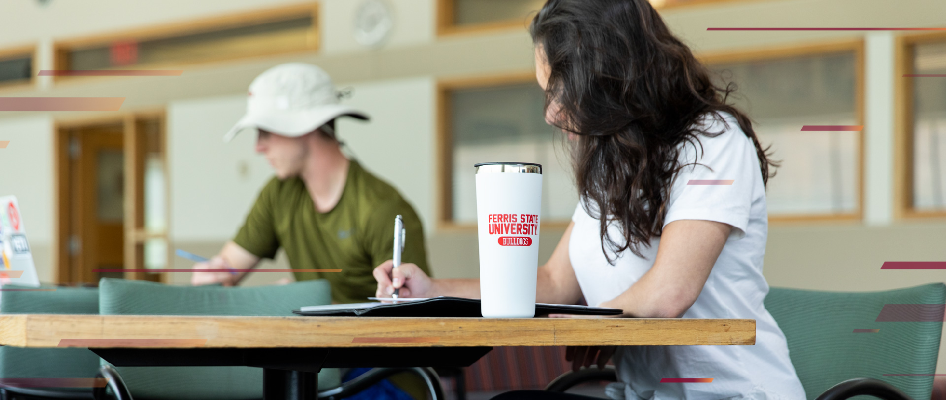 Student writing at table in library at Ferris