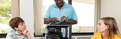 Students and professor working with a computer in a classroom setting