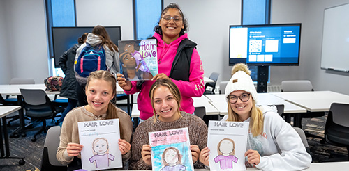 Students posing with coloring pages and a book