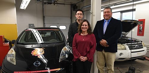 Students and faculty posed around an EV