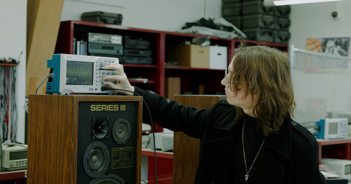 Ferris State University Electronics Automation and Engineering Technology student adjusting monitors for equipment in a lab. Ferris State University Electronics Automation and Engineering Technology student adjusting monitors for equipment in a lab.