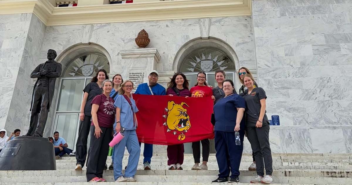 a group of ferris state university students and faculty studying abroad standing next to a building