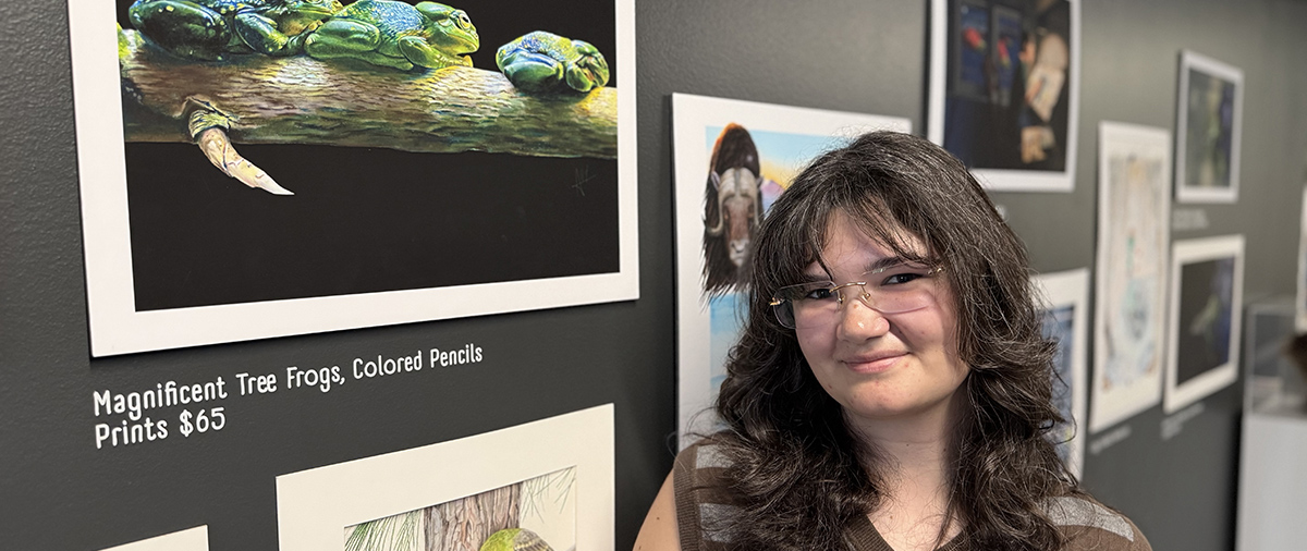 Ally Grant standing next to her gallery on the third floor of the Kendall College of Art and Design.