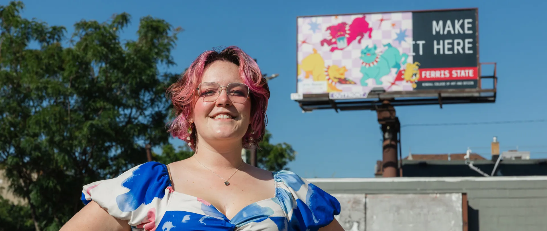 a student standing in front of a billboard featuring her artwork