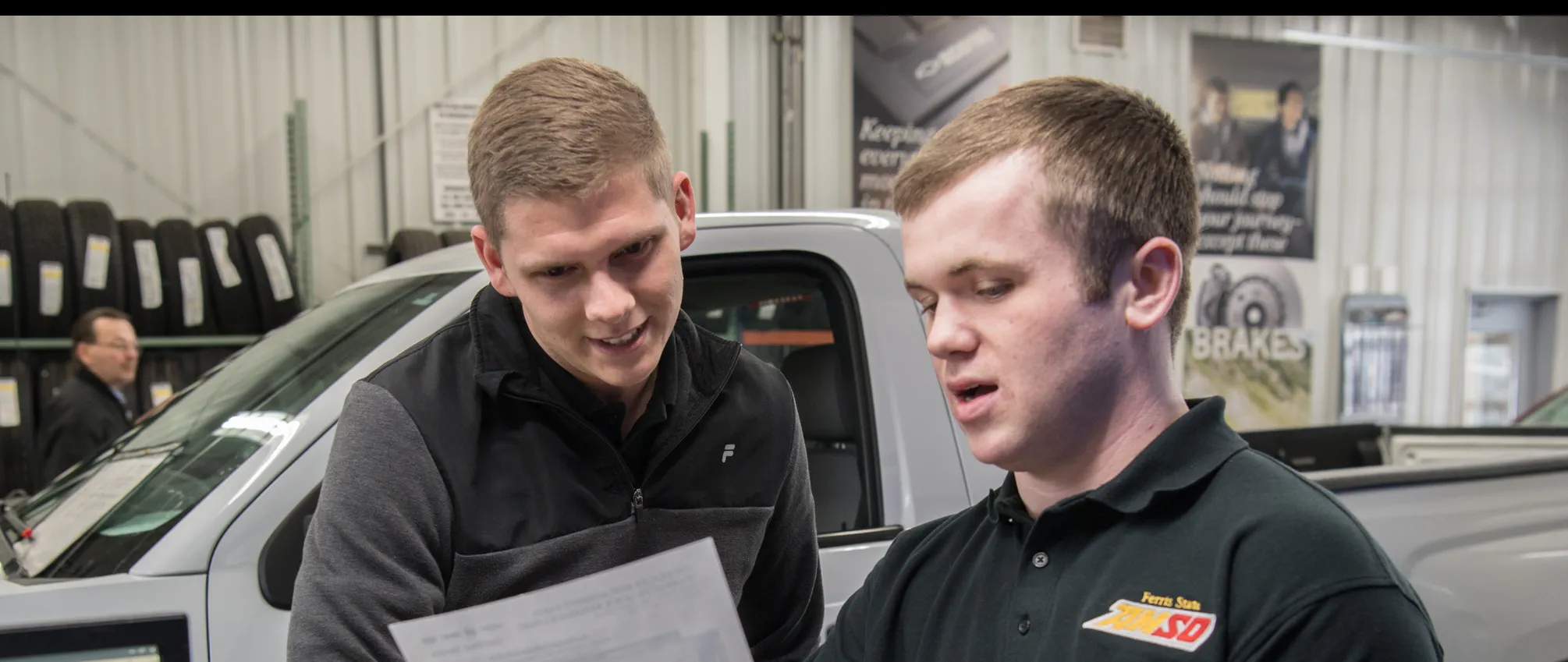 students in a body shop looking at a piece of paper