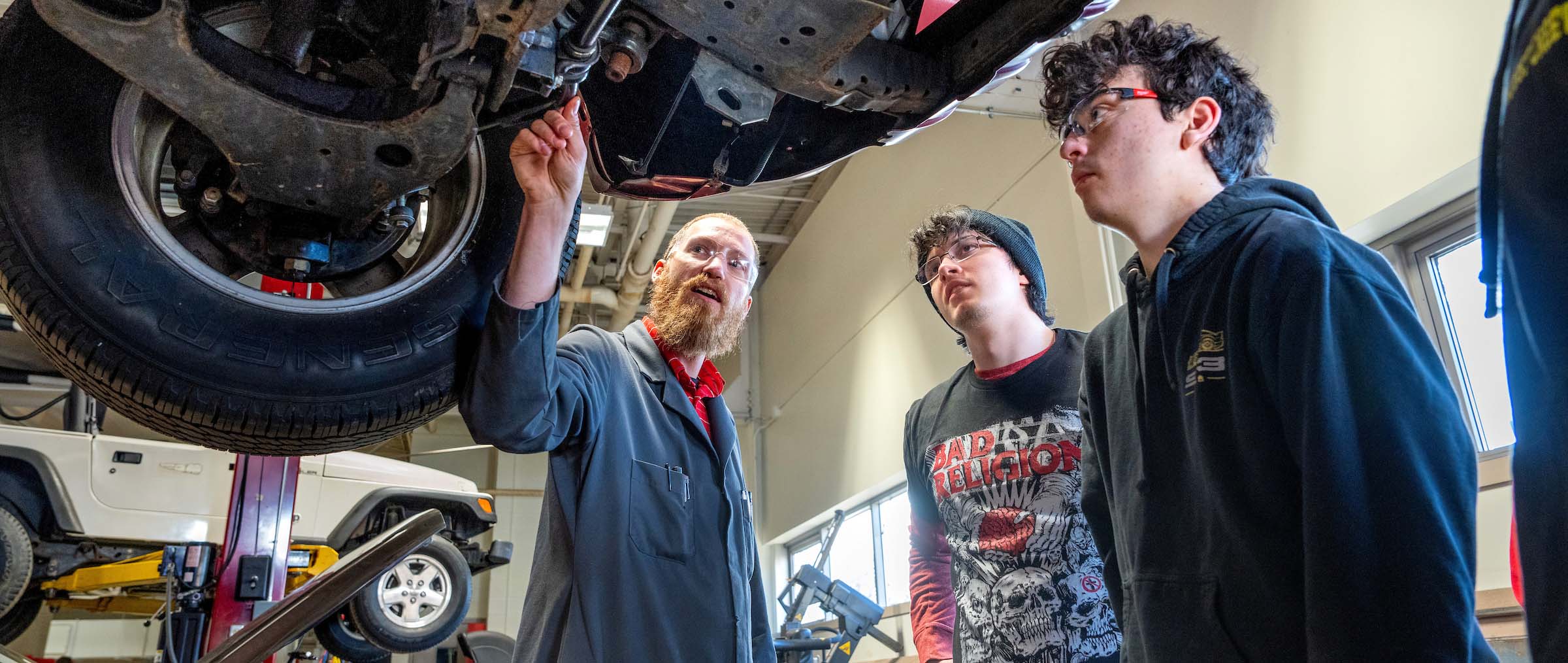 Professor and students examining the undercarriage of a vehicle