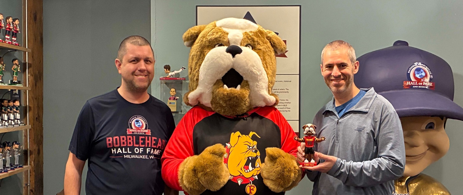 Brutus holding his likeness bobblehead standing with Phil Sklar and Brad Novak 