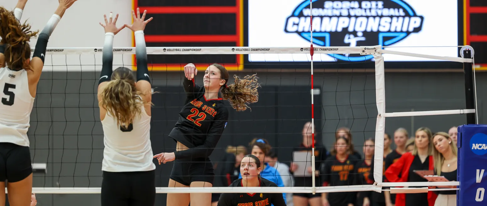 volleyball player spikes ball over the net