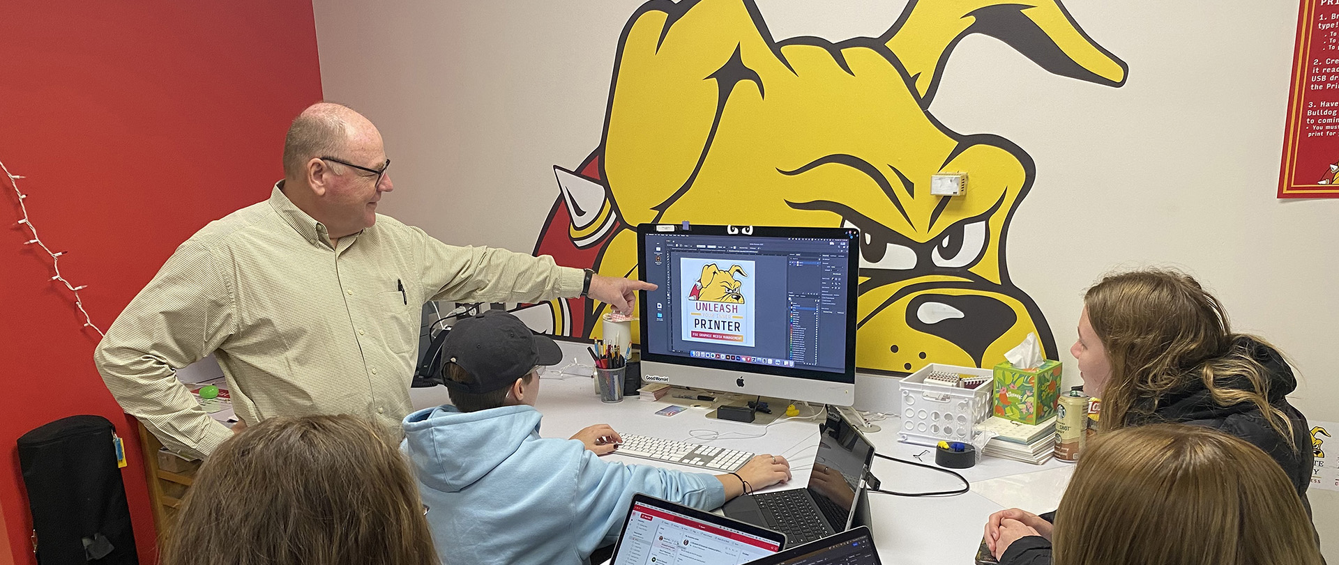 Students and instructor gathered around a computer on the campus of Ferris State University in Big Rapids MI