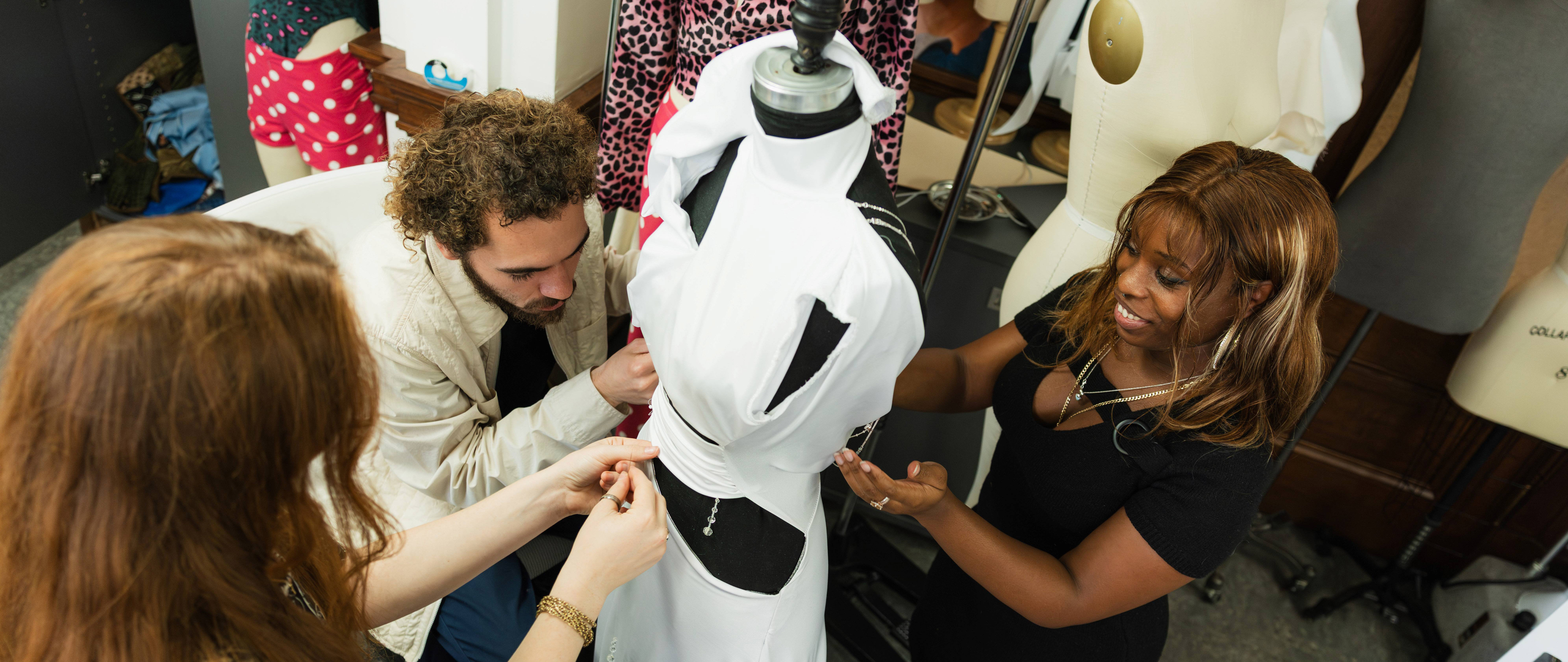 students working on a dress on a mannequin