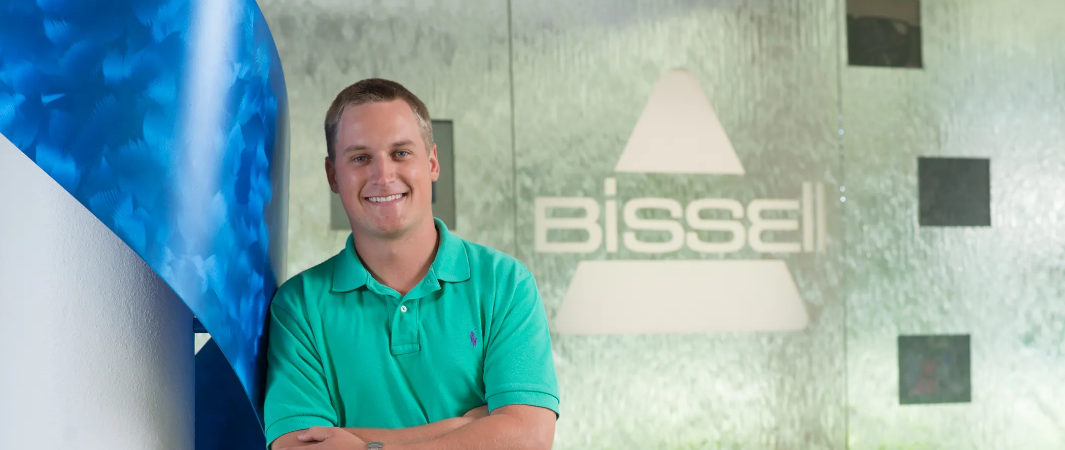 male student standing in front of a sign at an internship