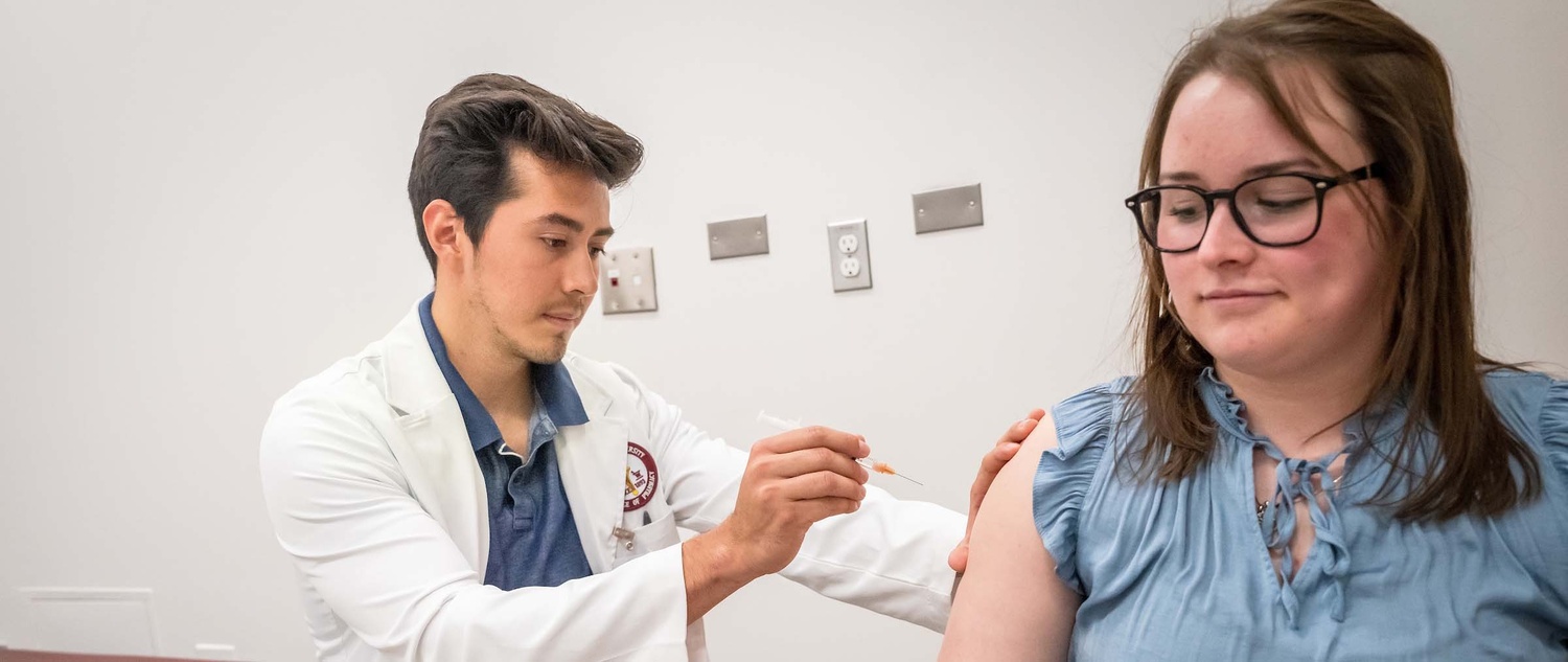 Pharmacy student administering a shot to a patient