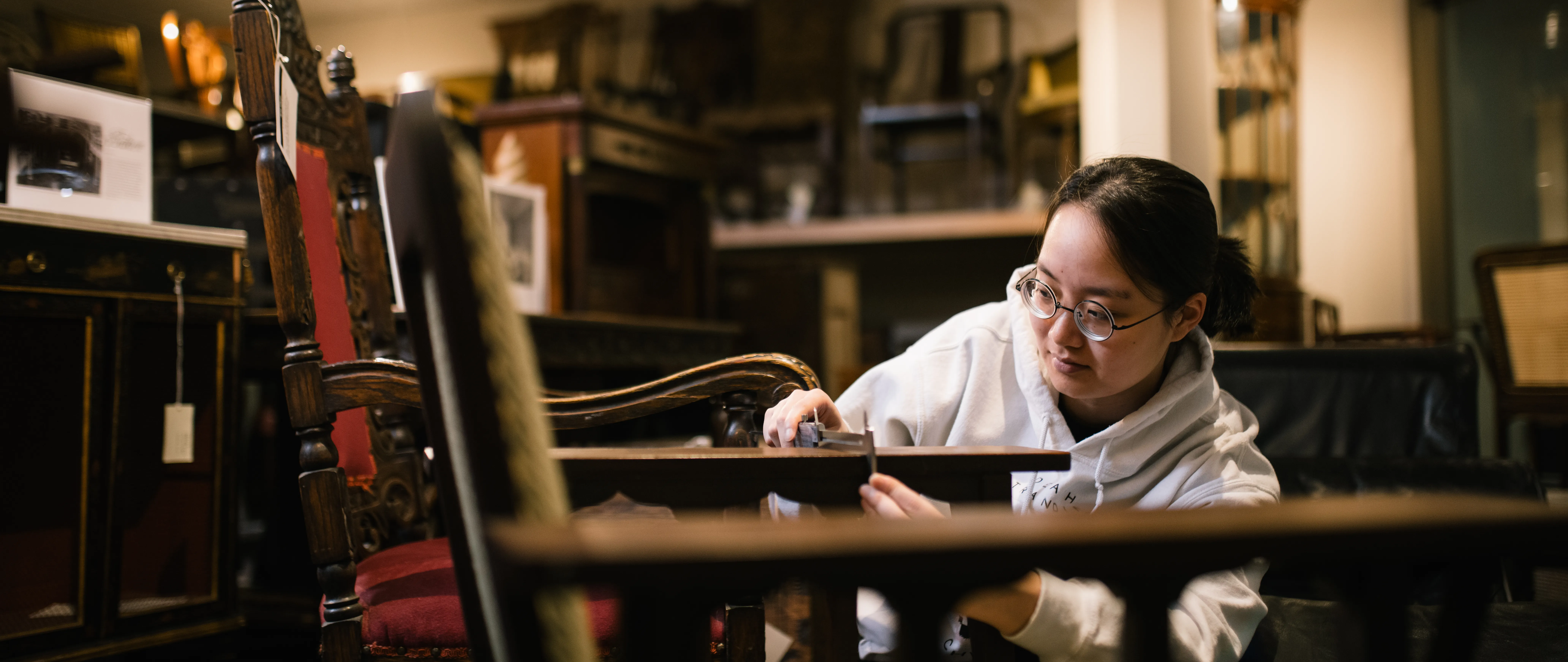 Student measuring the dimensions of a chair