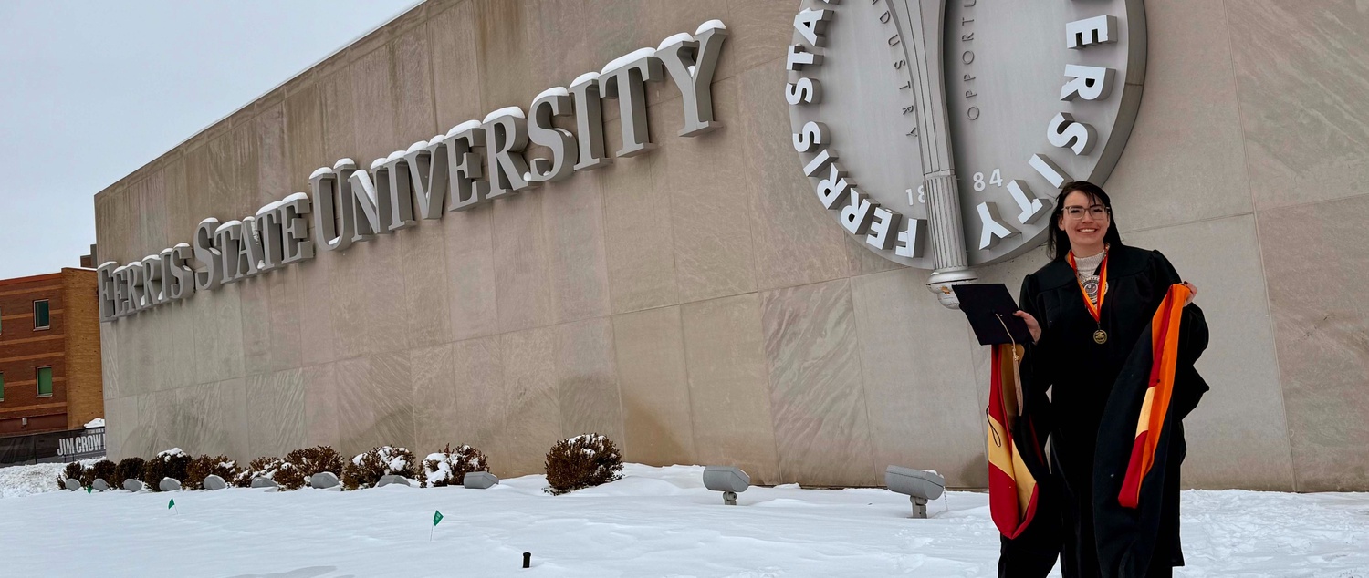 Ann Puruleski standing in front of the Ferris State University sign with degree in hand
