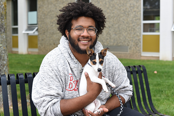 Alando Steele with his pet dog in front of a pet-friendly floor in a student residence hall at Ferris State University