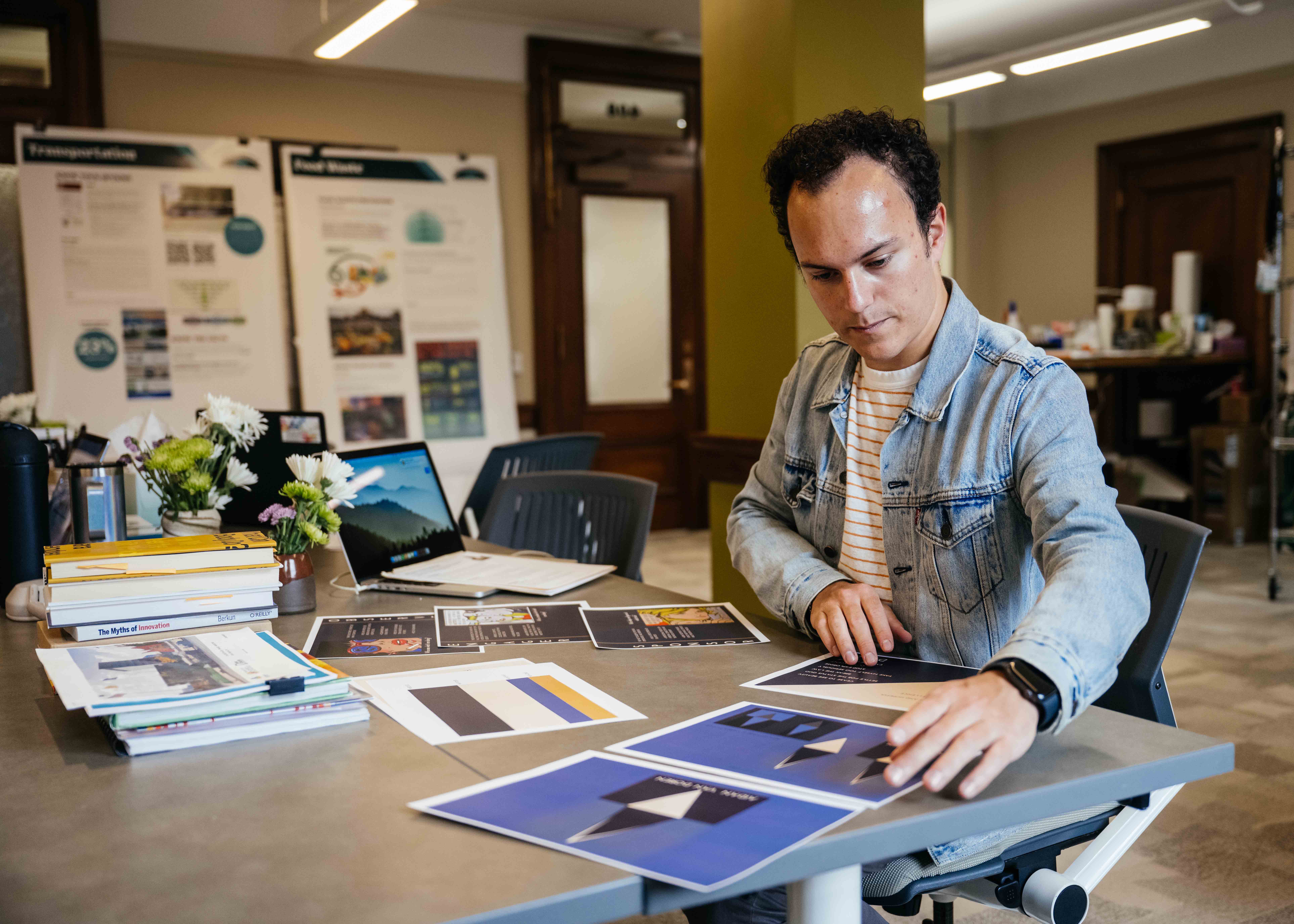 a student working at a desk with a ton of papers around him