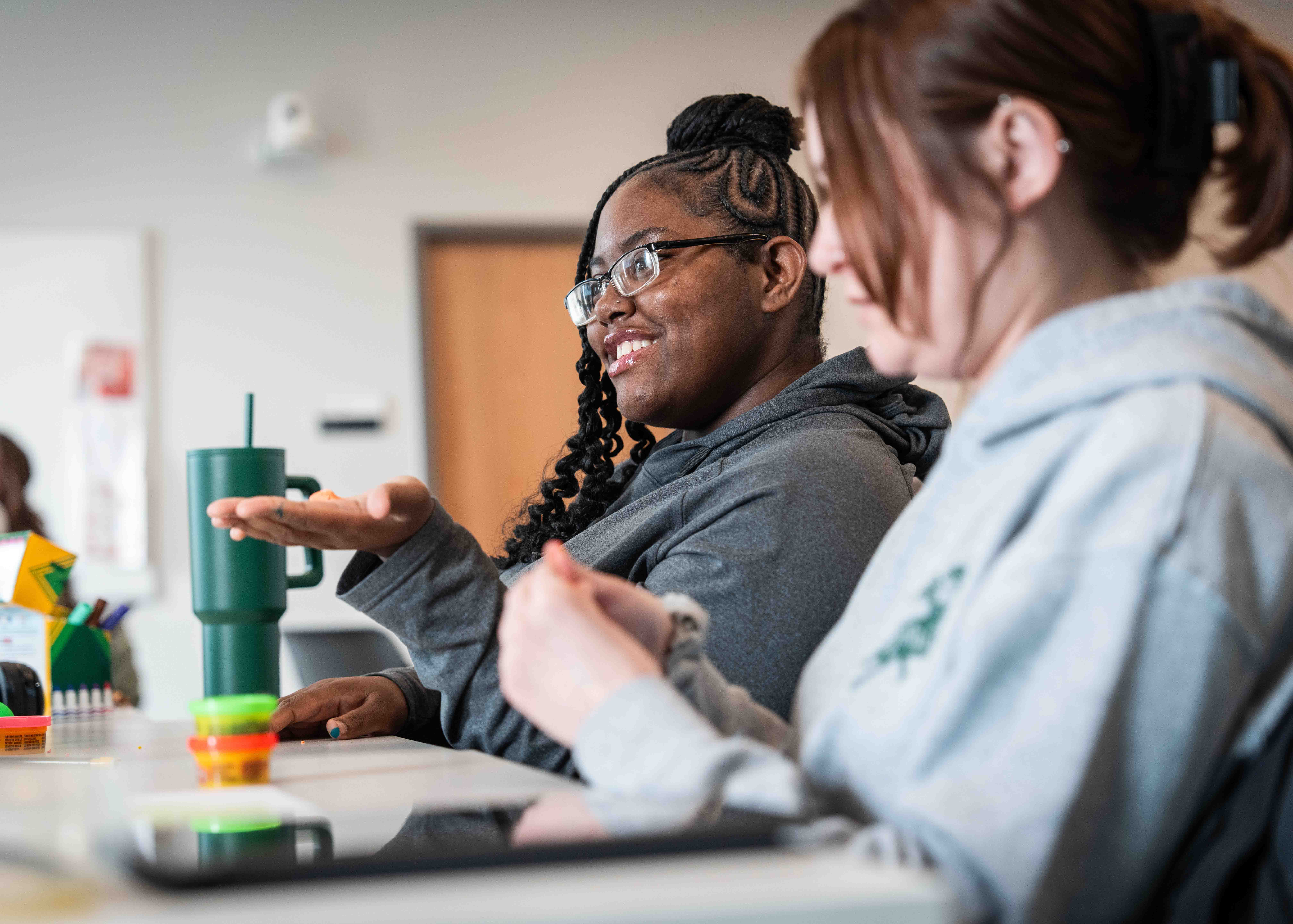 student in a classroom holding playdoh